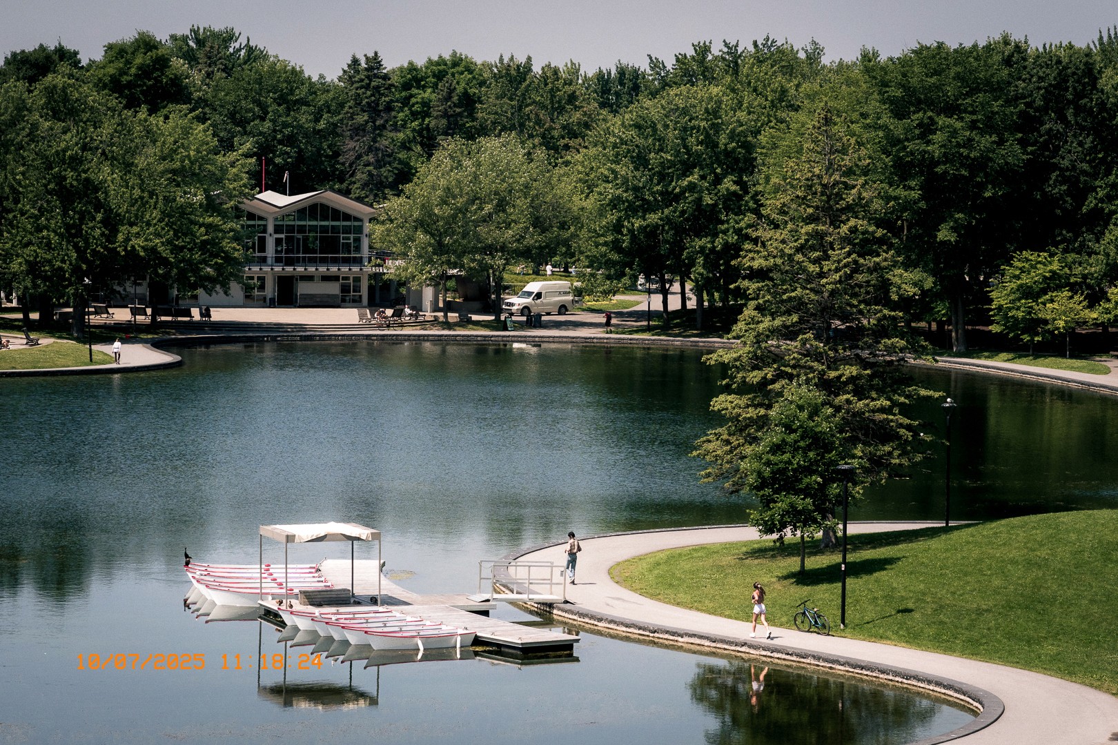 Vue paisible du Lac aux Castors avec embarcations amarrées et promeneurs.