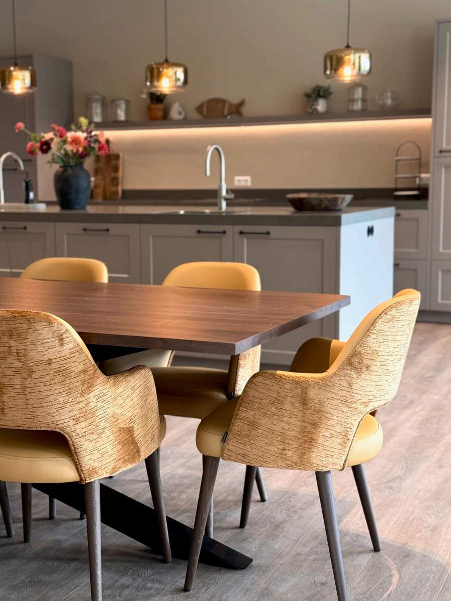 grijze keuken met tafel en oker gele stoelen 