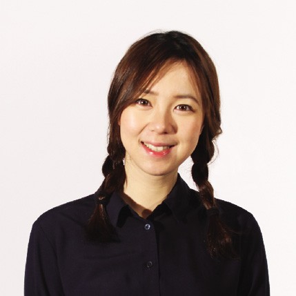 A woman with dark brown hair styled in two braids with small dark bands. She is wearing a dark navy blue button-up shirt against a plain white background. She is smiling and looking directly at the camera.
