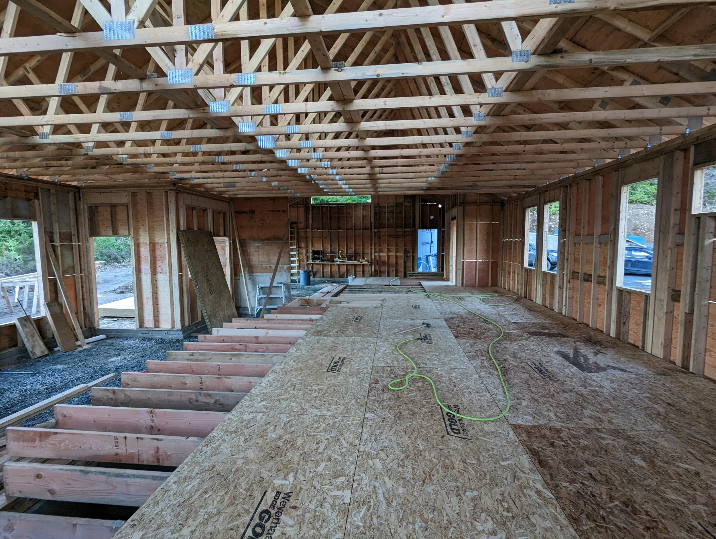 Modern two-story home with large glass windows, warmly lit interiors, and a balcony. Surrounded by trees and a manicured lawn at dusk. Cozy ambiance.