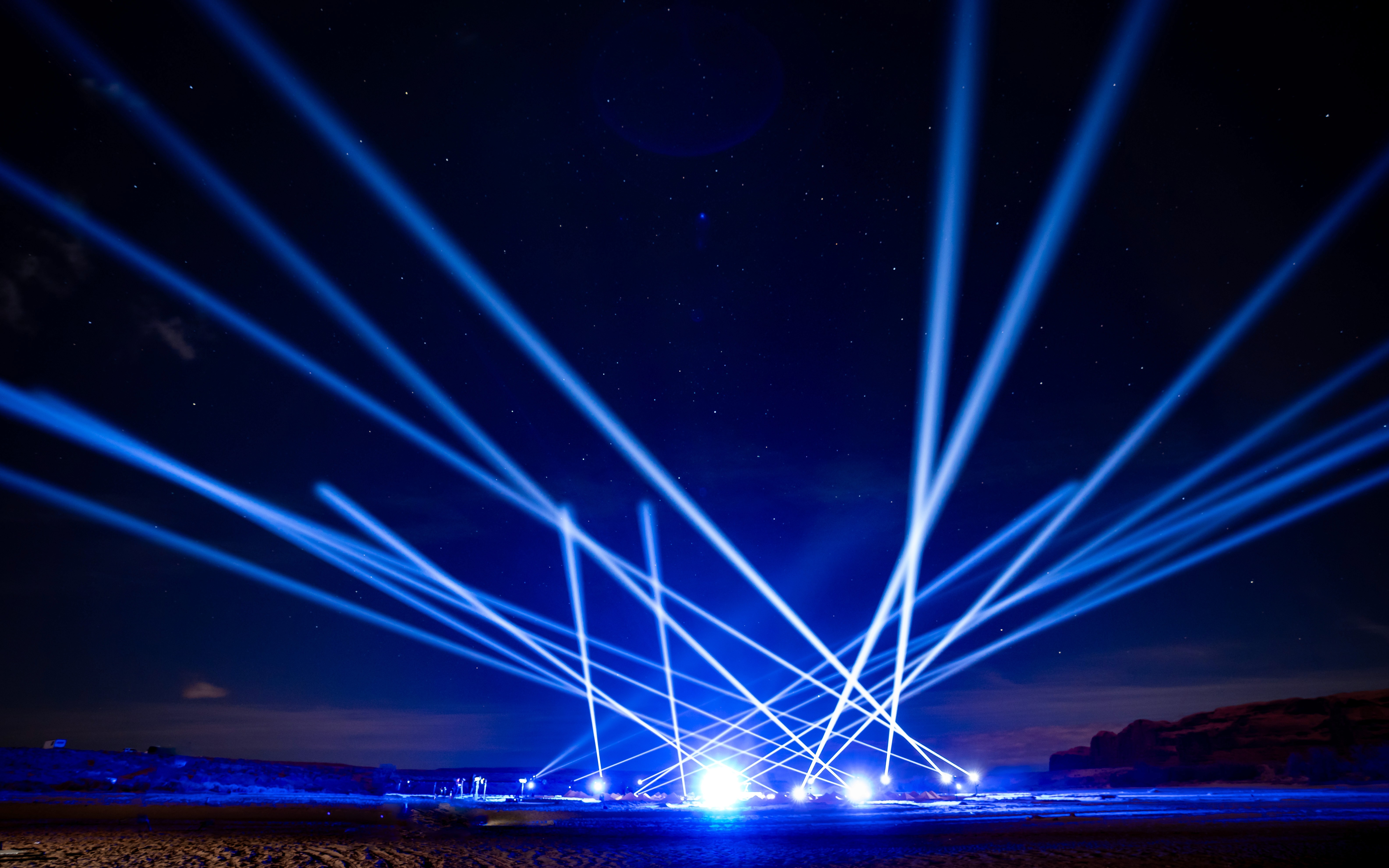 Dozens of beams of blue light shoot up in the night sky during a live performance by the band ARIZONA