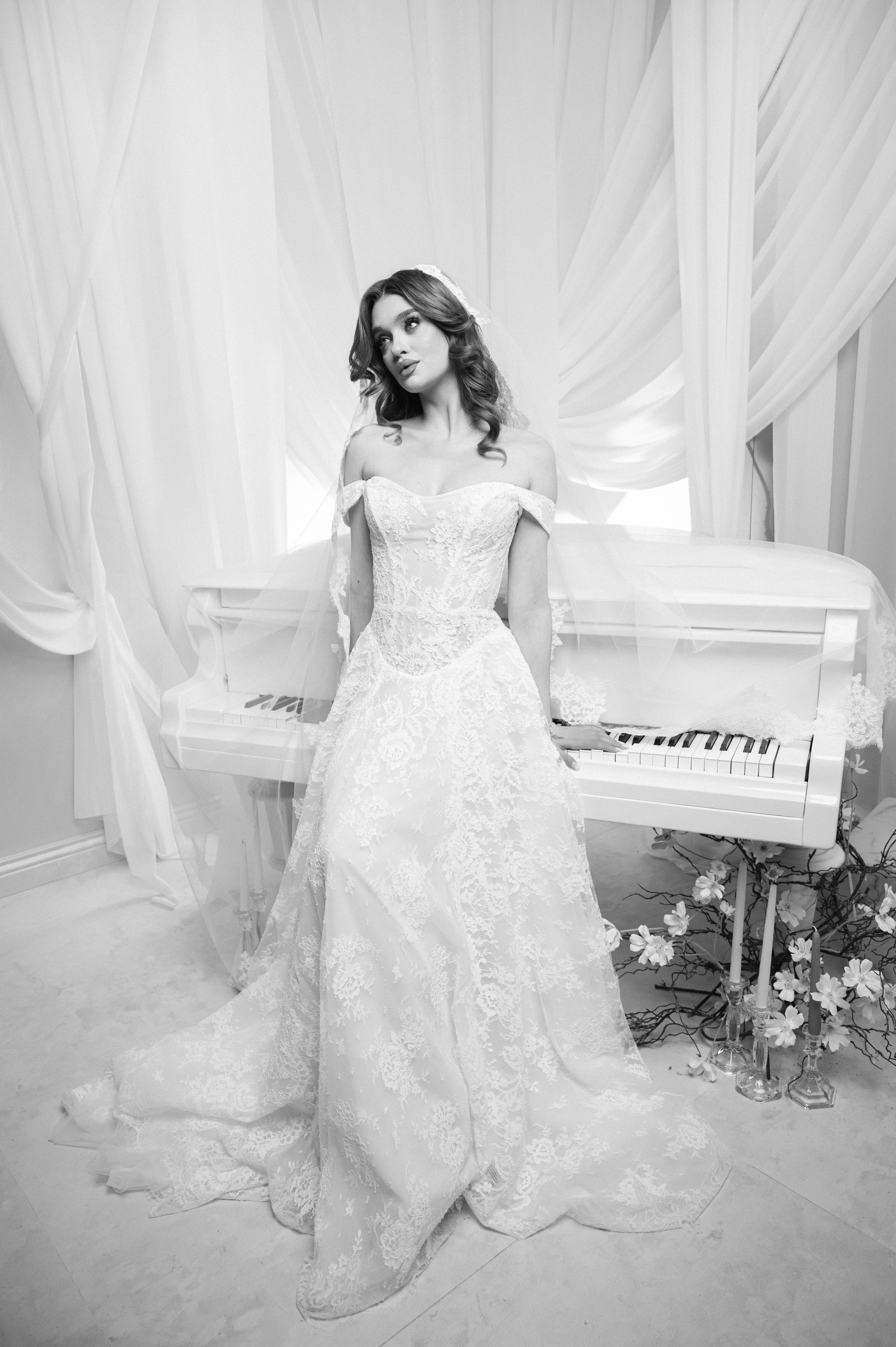 Mireasă fotografiată full body lângă un pian alb într-un decor elegant, ședință foto bridal în București