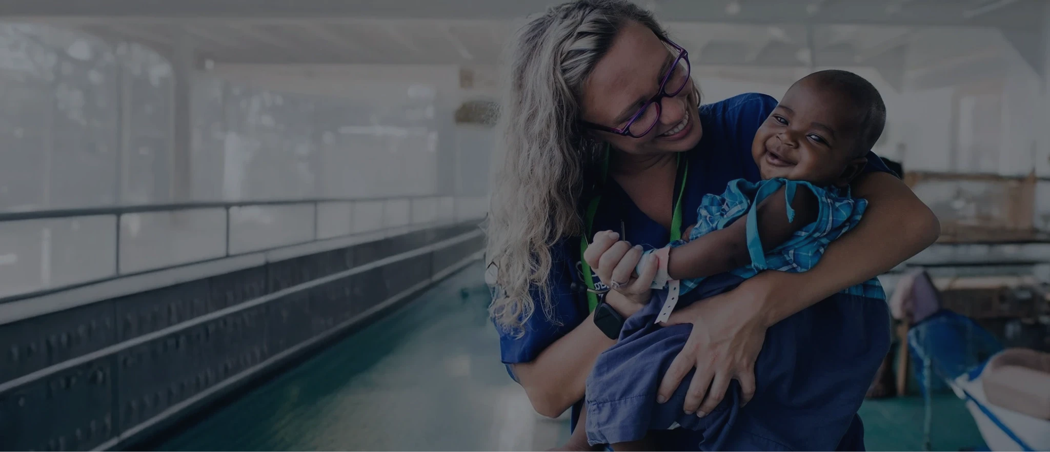 Volunteer holding a baby while smiling