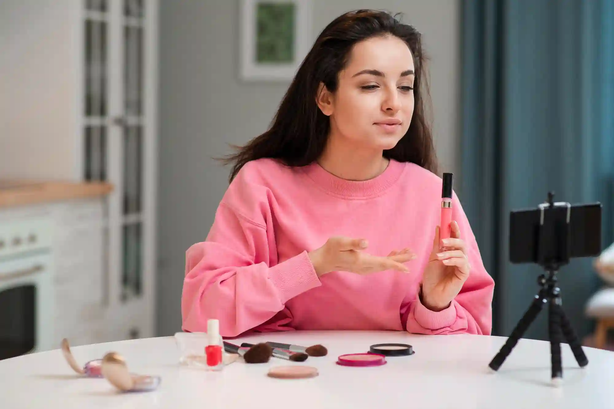 A young woman creating a beauty or makeup tutorial video using her phone mounted on a tripod.