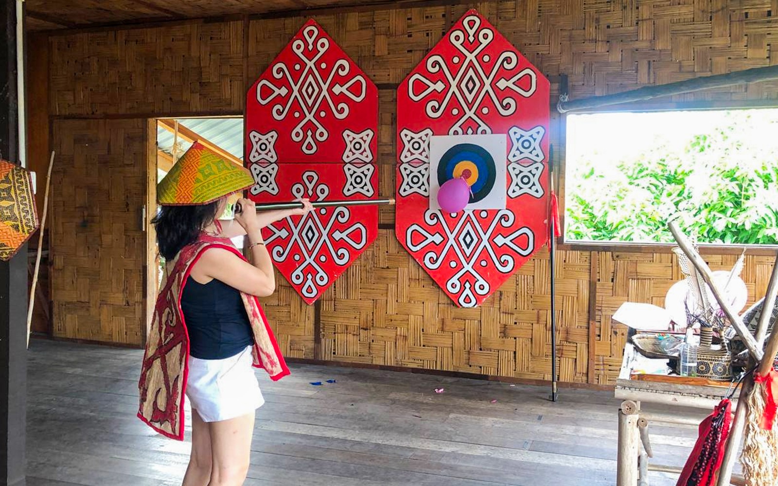 Person participating in blowpipe activity at Koisaan Cultural Village, Malaysia.