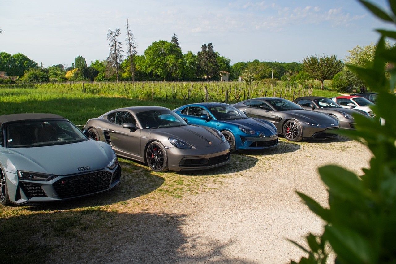Voitures de sport garées en ligne sur un terrain en gravier à la campagne, road trip Auvergne Périgord