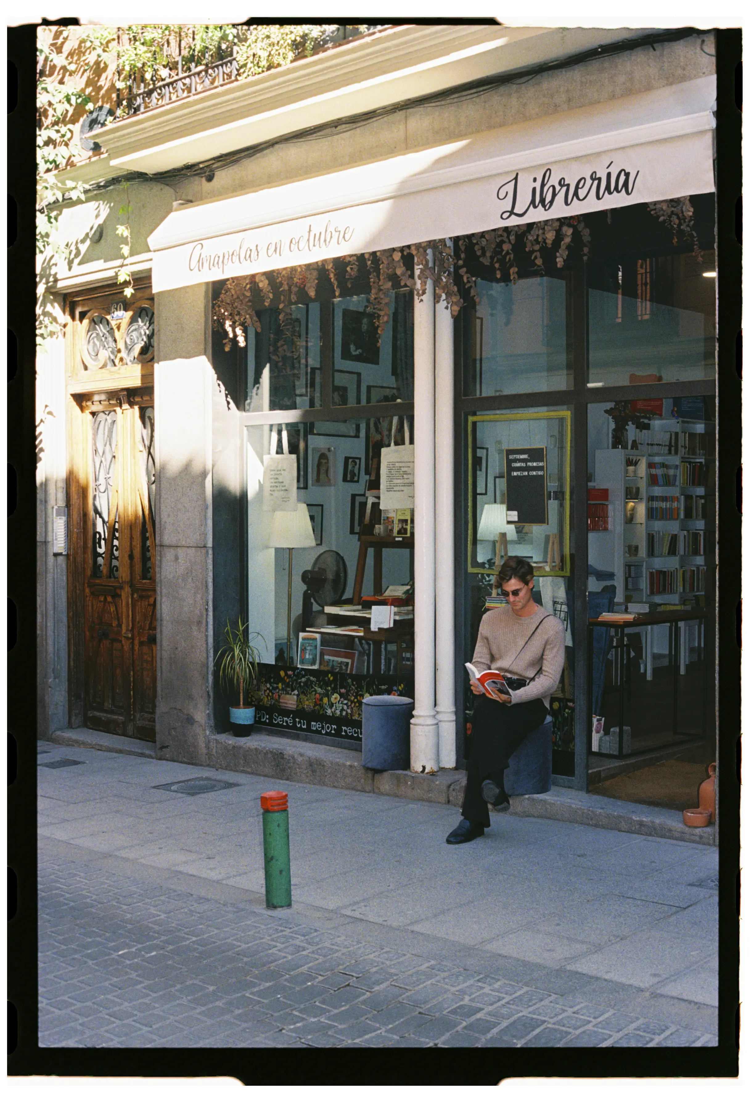 hombre joven leyendo frente a la puerta de libreria amapolas en octubre