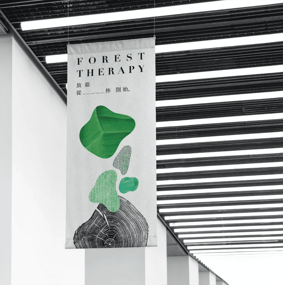 這張圖片展示了「森林療癒」的視覺設計,一個垂掛的布,上面的設計元素包括抽象的綠色形狀和木材年輪圖案,象徵自然和樹木,強調森林療癒的概念。