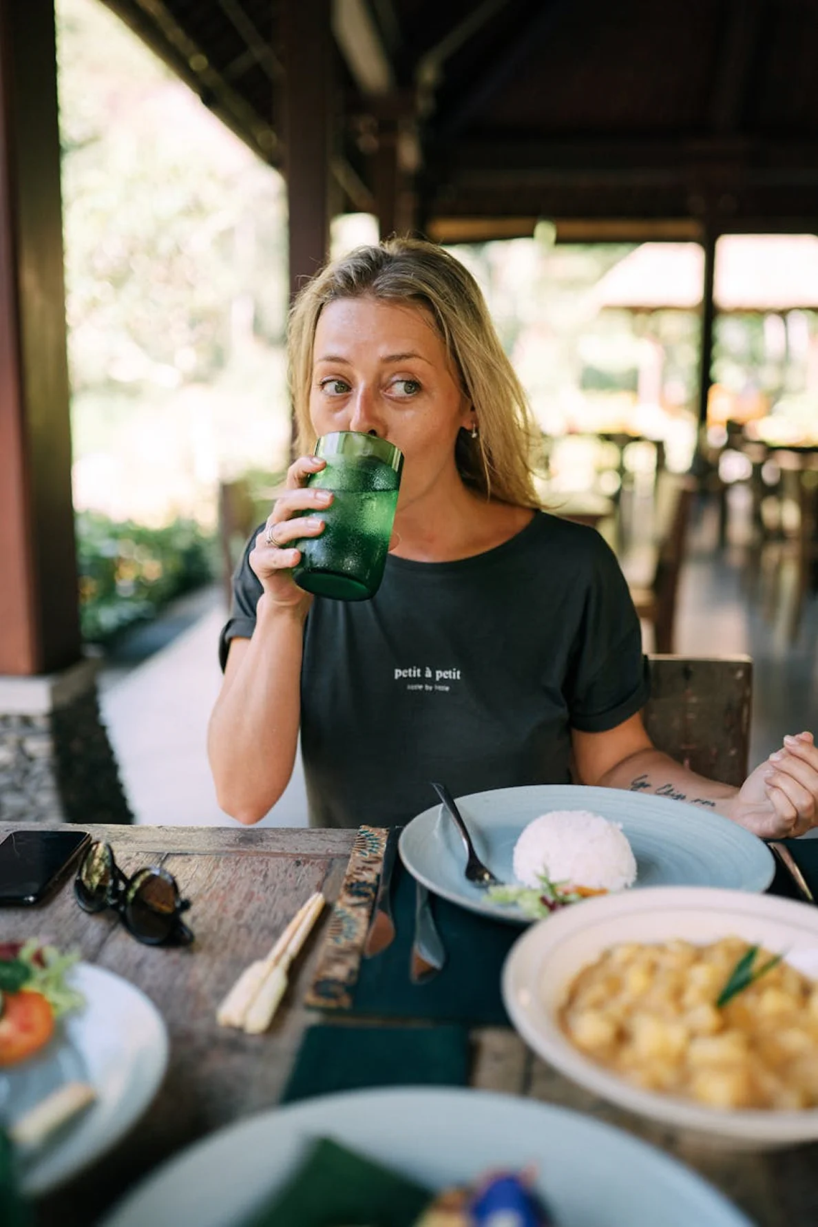 Guest enjoying a fresh drink and meal at an open-air tropical restaurant.