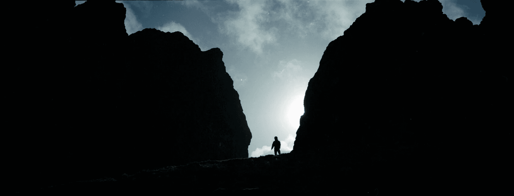 Fujifilm TX-1 panoramic photo of a person standing in between two high peaks in Scotland, with strong backlight and strong use of the power of imagination