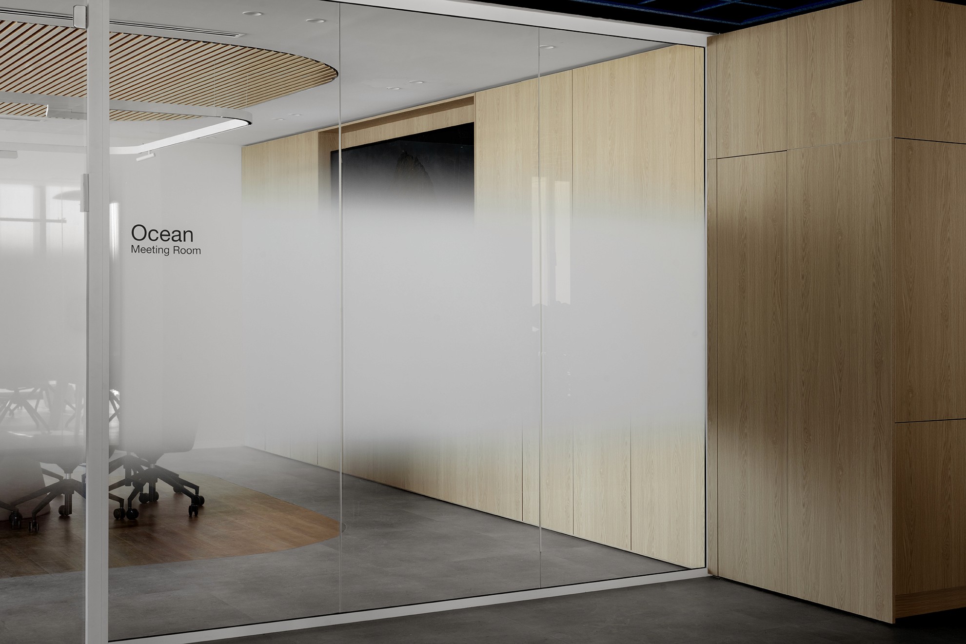 שילוט ופרטיות: כניסה לחדר ישיבות "Ocean" עם מחיצת זכוכית ומדבקת התזה מדורגת (Gradient Frosting), המעניקה פרטיות ויזואלית עדינה.