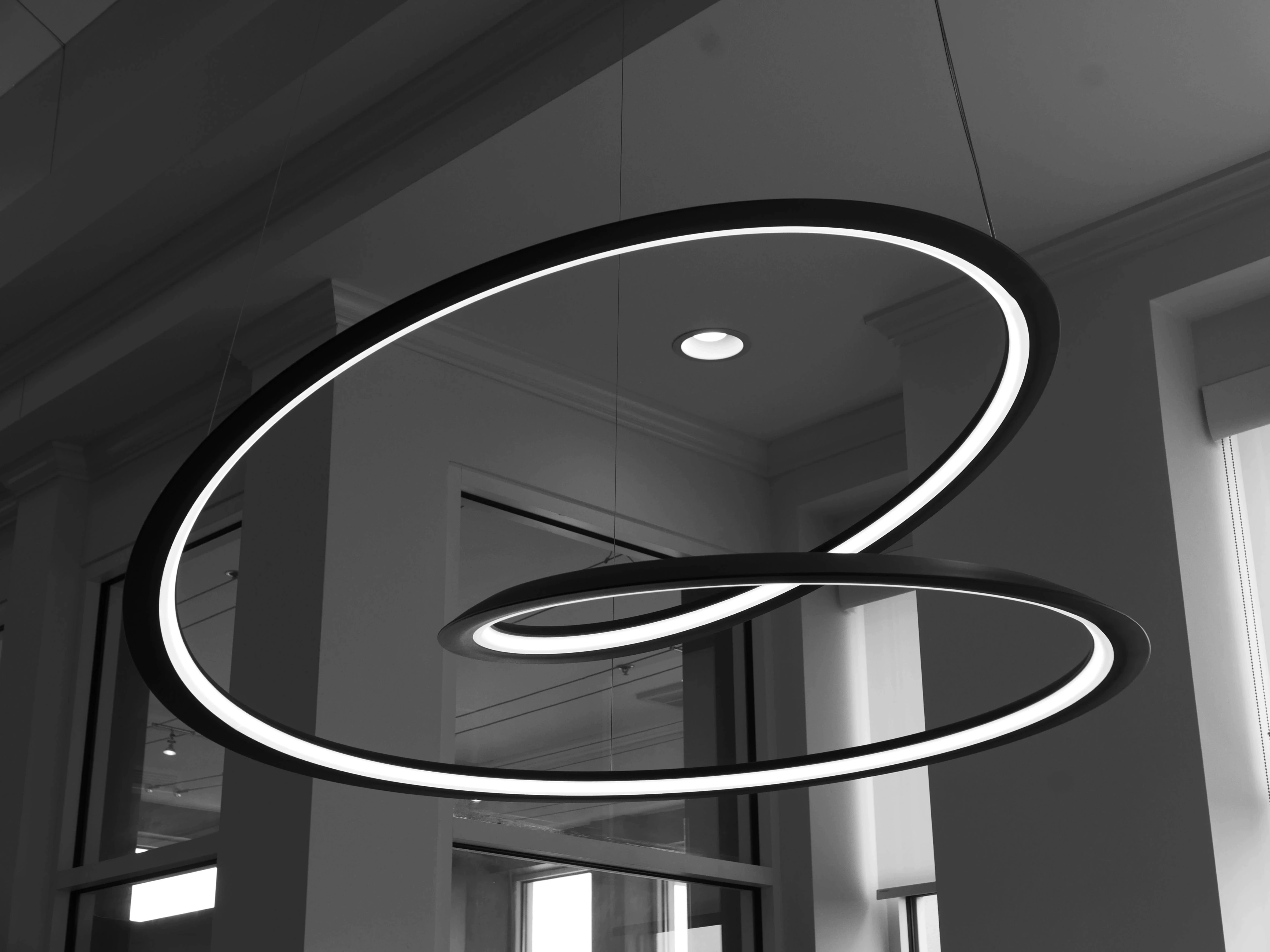 Abstract monochrome sculpture illuminated with flowing white LED light lines.