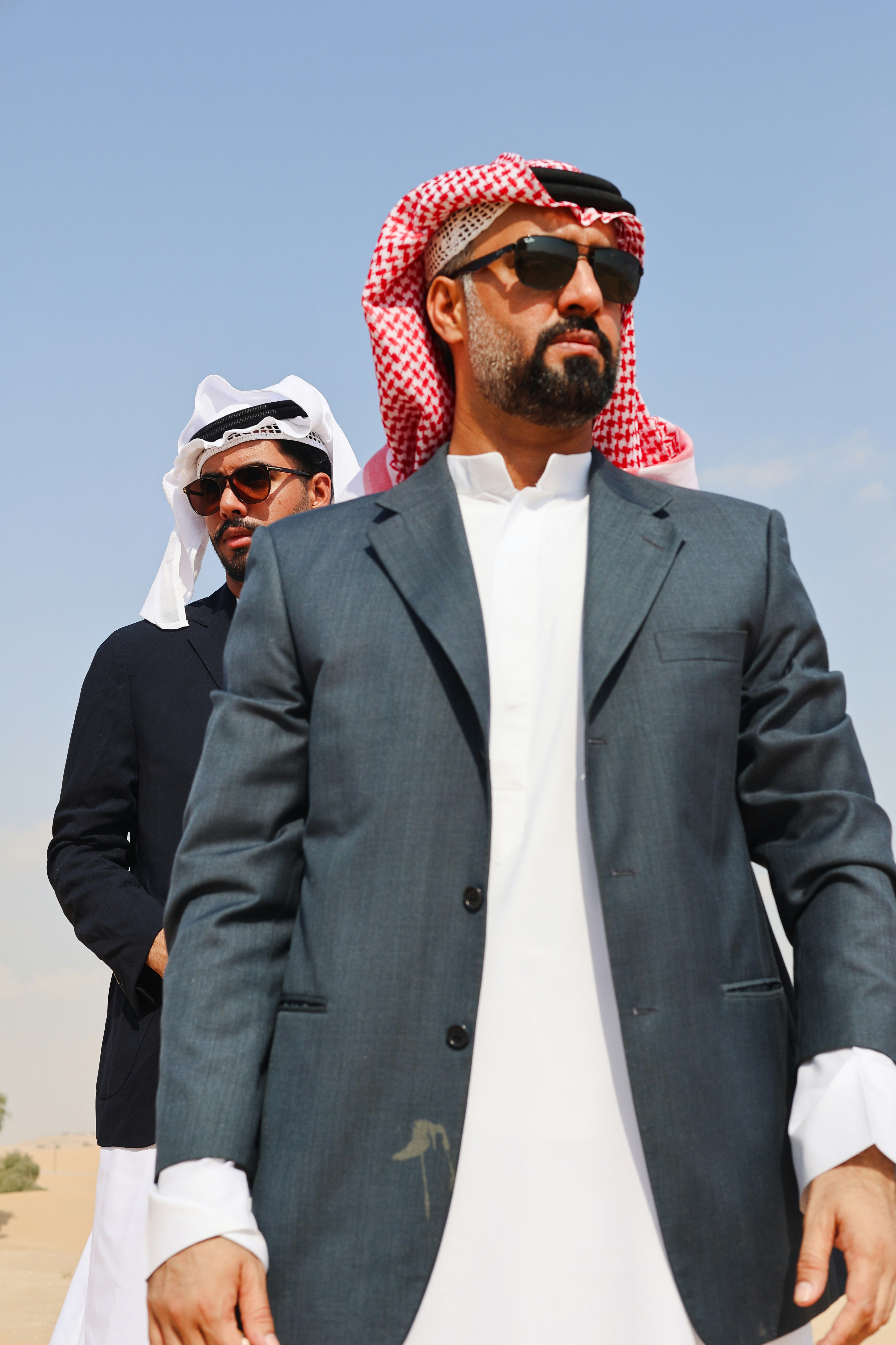 A man in a suit and sunglasses standing in the desert
