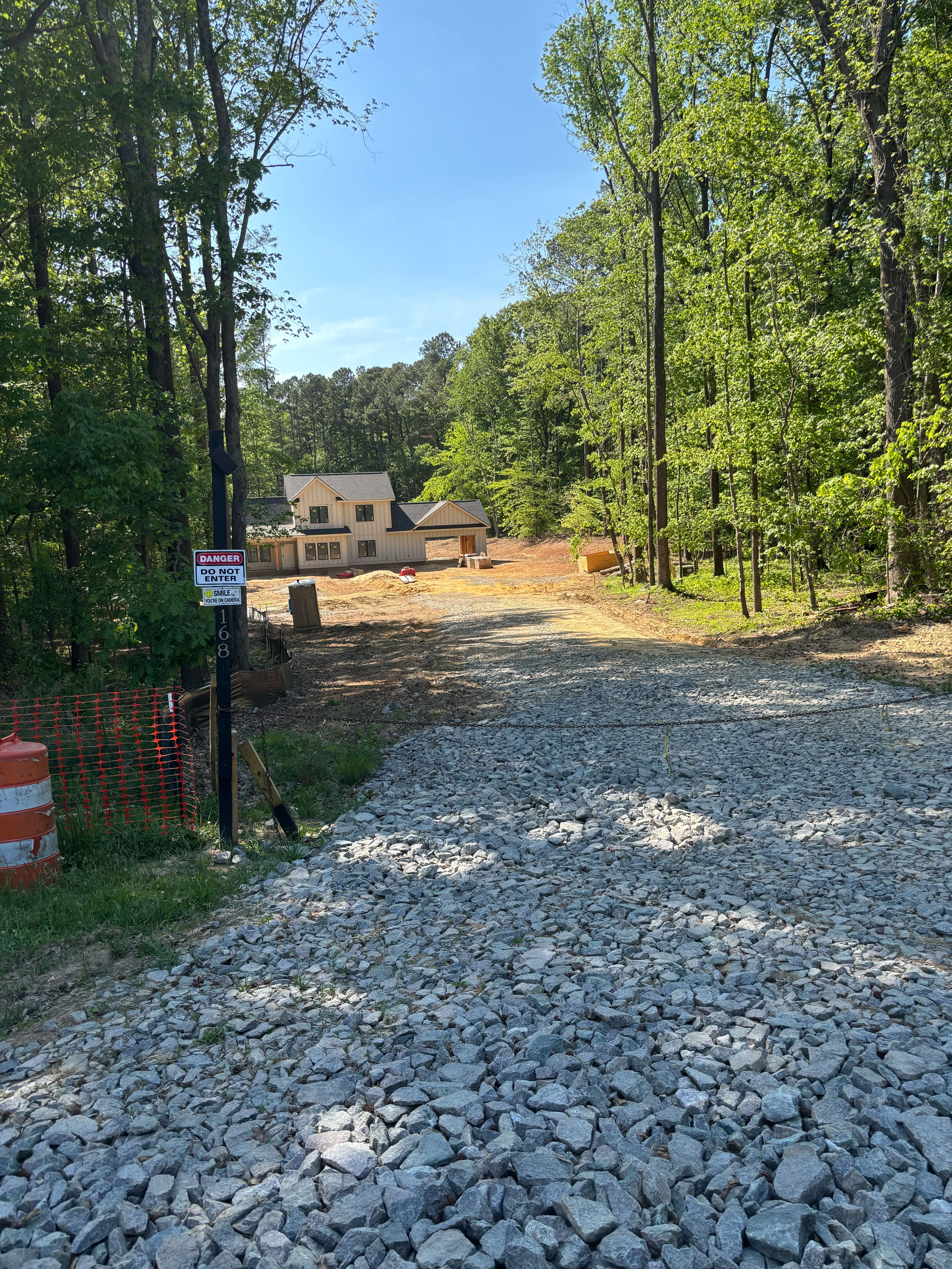 Custom home under construction nestled among trees in North Carolina with gravel driveway