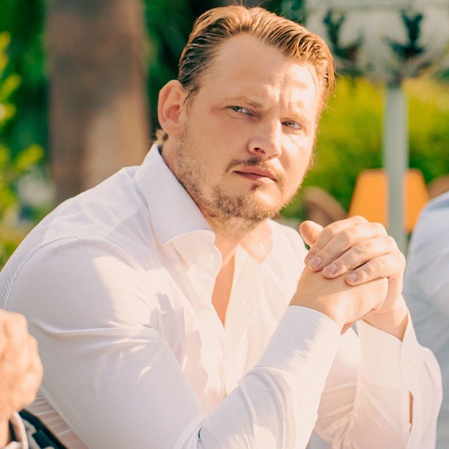 Portrait of a person in a pink sweater against a light background