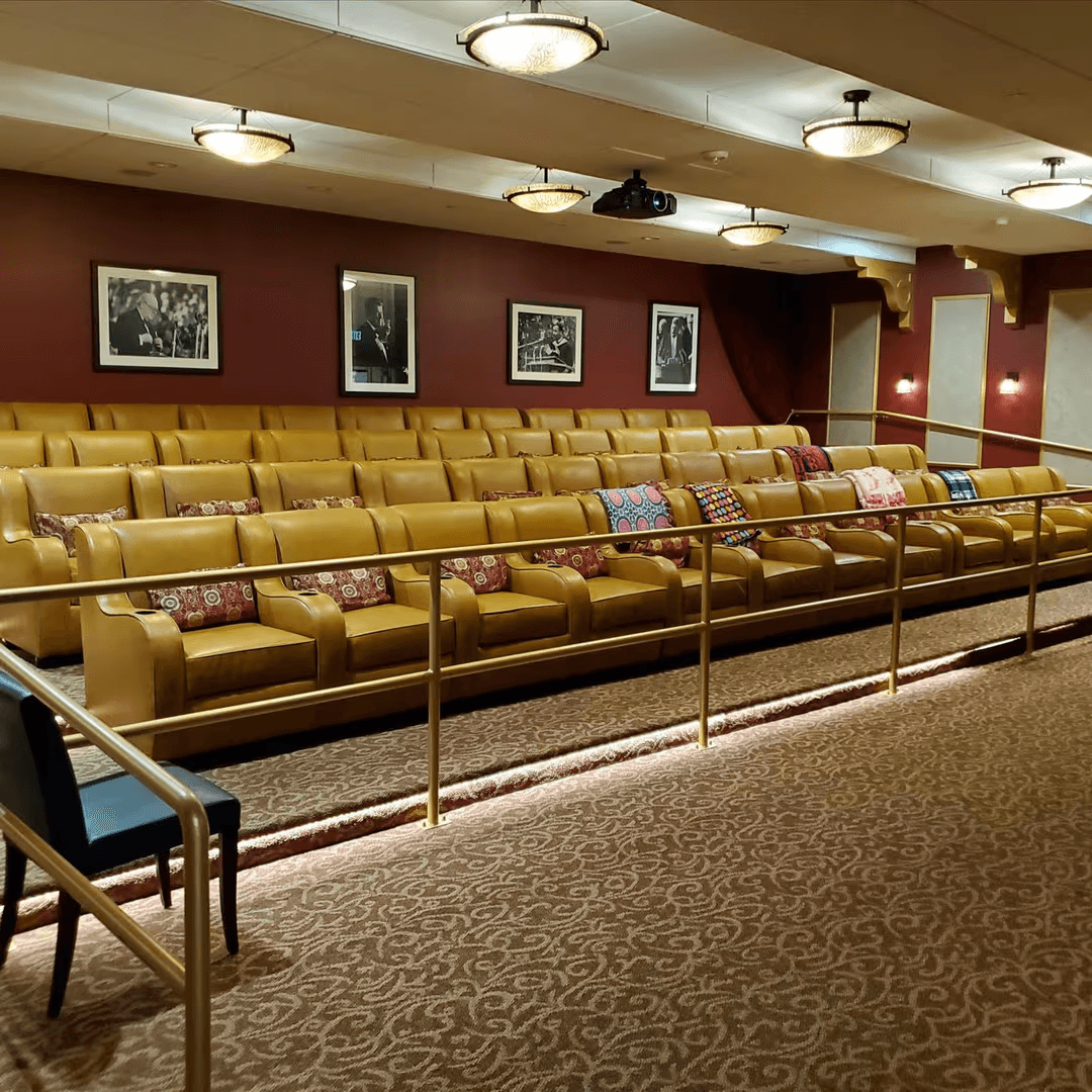 In-house movie theater with soft seating where assisted living and memory care residents gather for films and group activities.