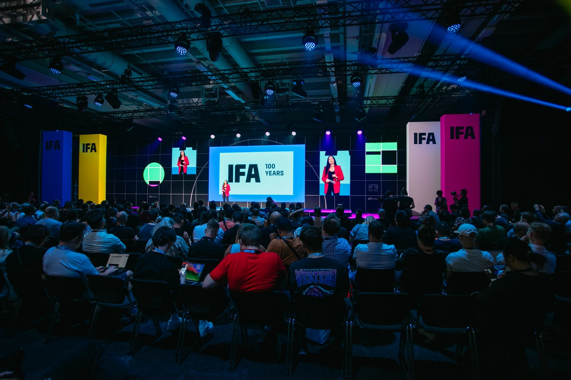 Keynote stage at IFA 2024 with „100 Years" branding, two speakers presenting in front of a fully seated audience inside the Berlin trade fair hall.