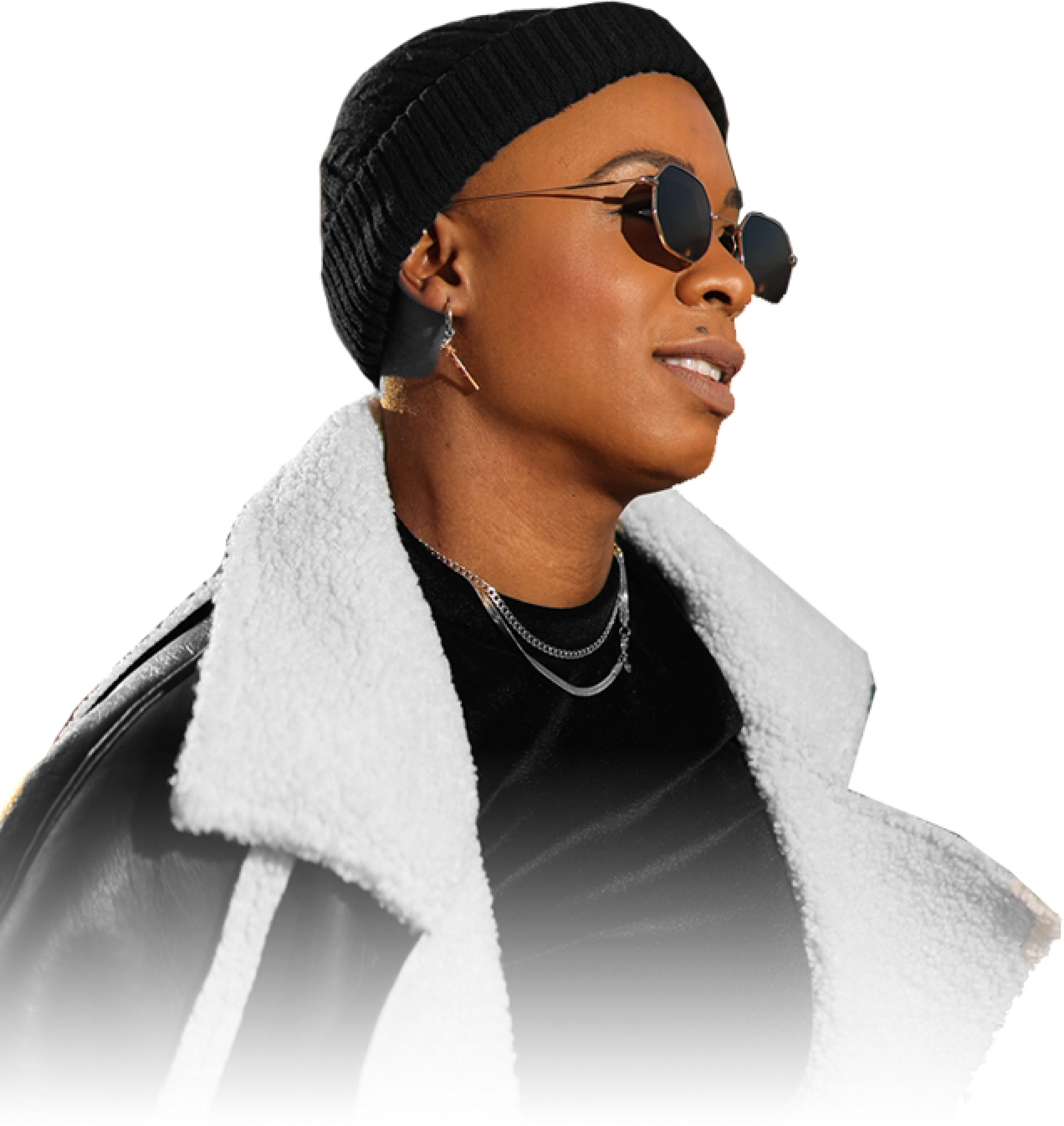 Ashleigh Warren, a person wearing sunglasses and a beanie, dressed in a stylish black outfit with a fur-trimmed coat.
