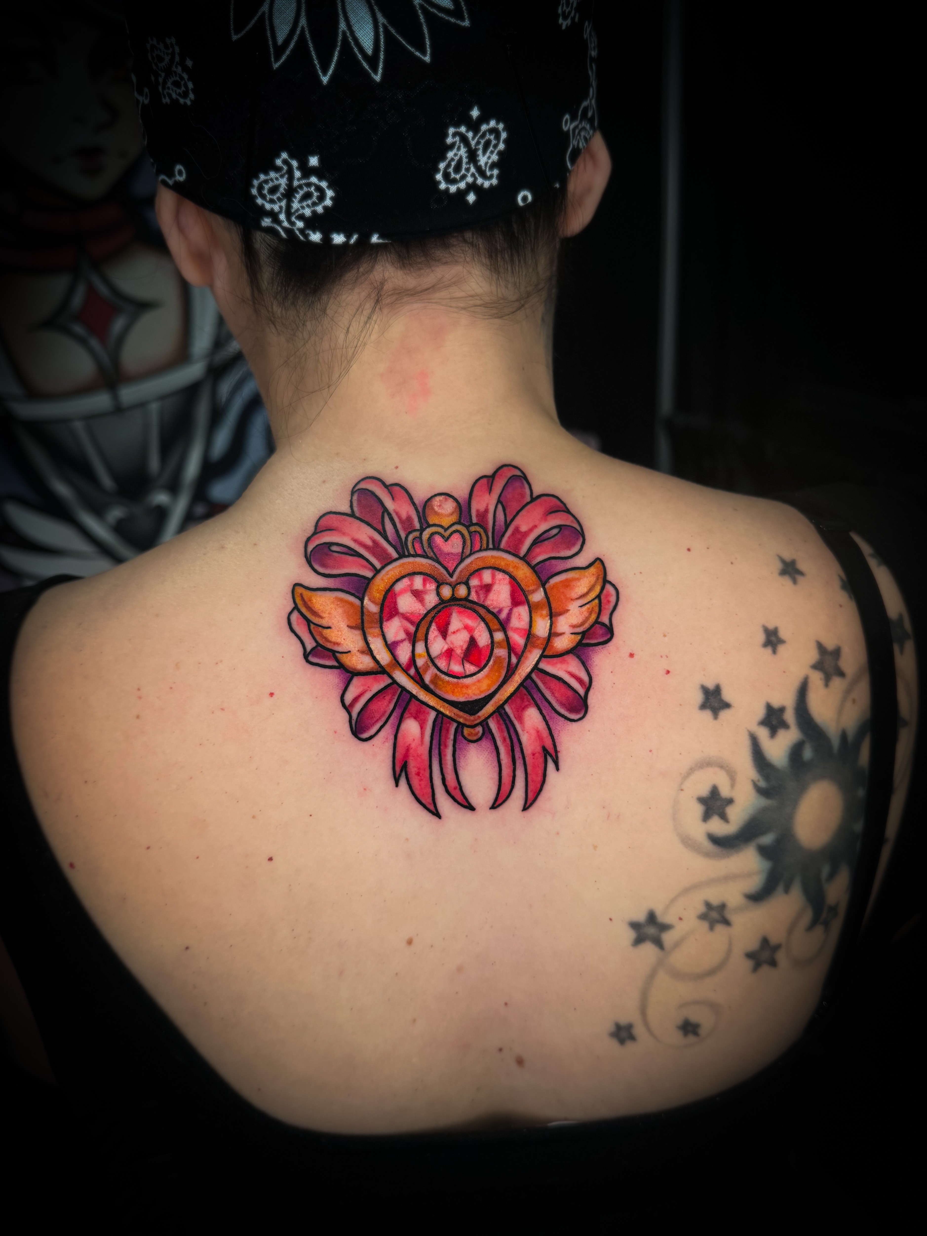 A vibrant tattoo of a chainsaw-like creature on a person's forearm. The tattoo is detailed with shades of orange, black, teal, and red.