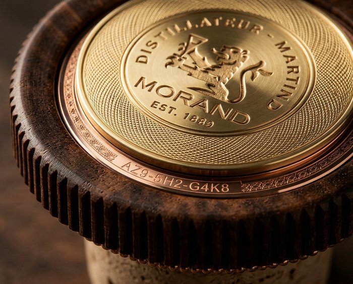 Close-up of a gold and bronze component with embossed text reading "MORAND EST. 1889" and an alphanumeric code "AZ9-5H2-G4K8" on the side.