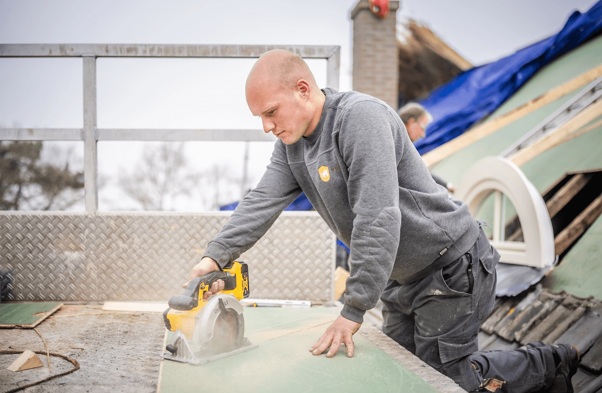 Rietdekker van Rietdekkersbedrijf van Dijk werkend aan de vervanging van dakpannen met een rieten dak