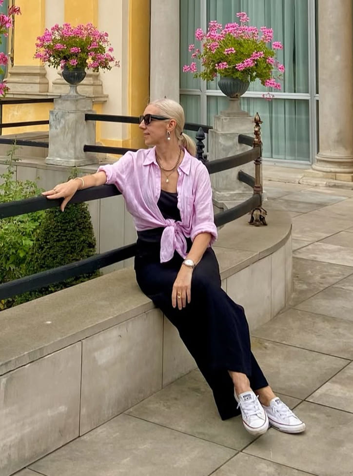 Black-and-white portrait of a man with an afro in motion, wearing a hoop earring and chain necklace, against a light gray background.