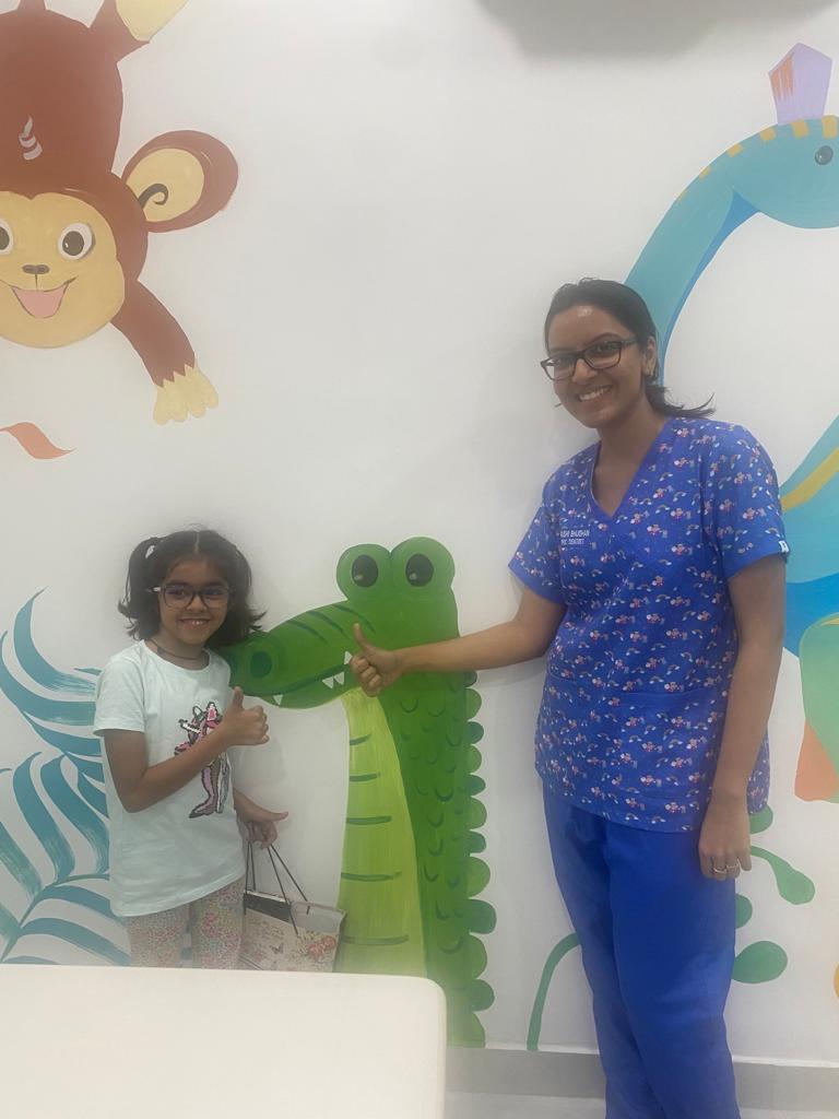 Dr. Urvashi and a child beside colourful animal murals at Cheery Smiles