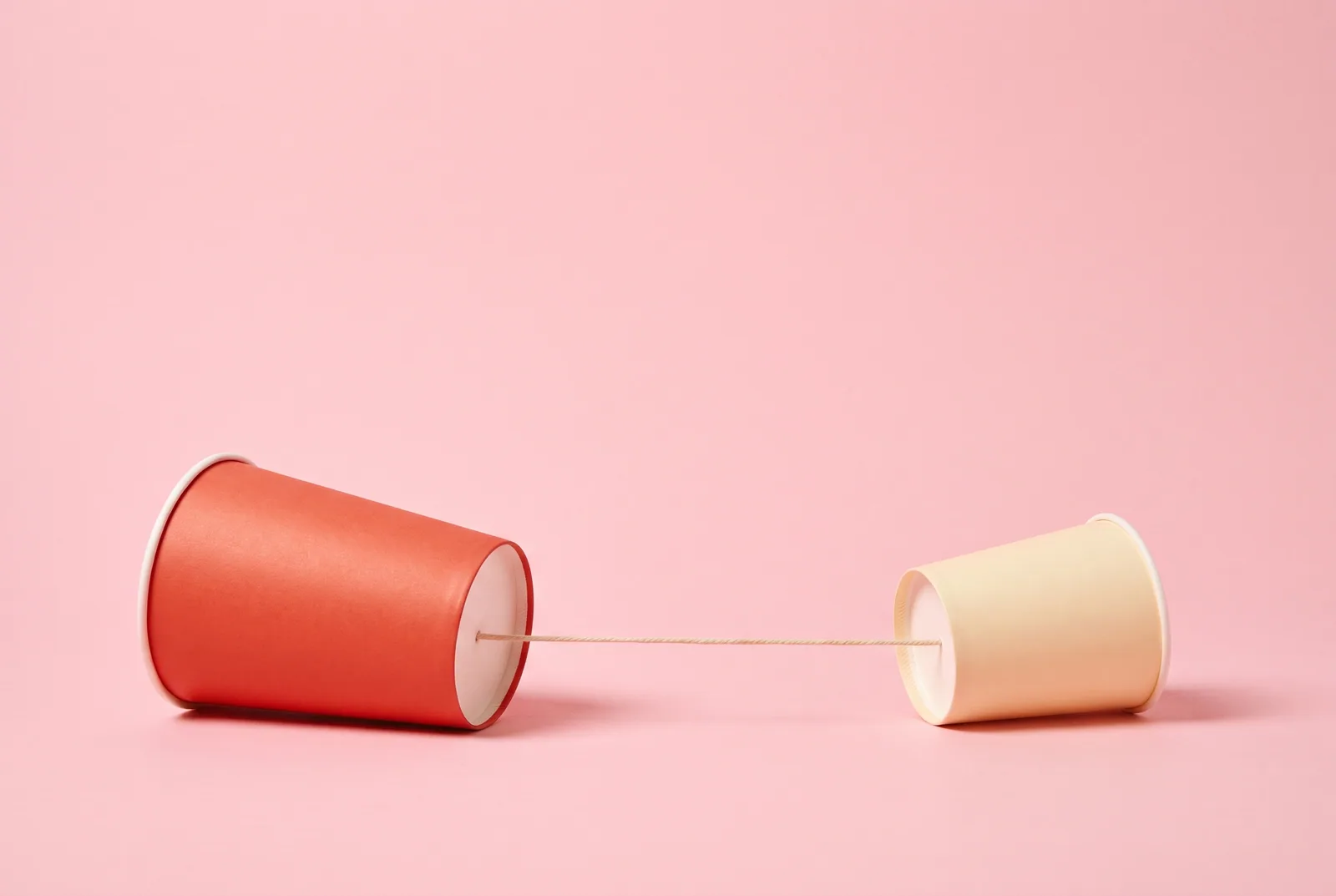 Two paper cups joined by a string telephone, a playful symbol of age-by-age scripts for talking to your son about porn
