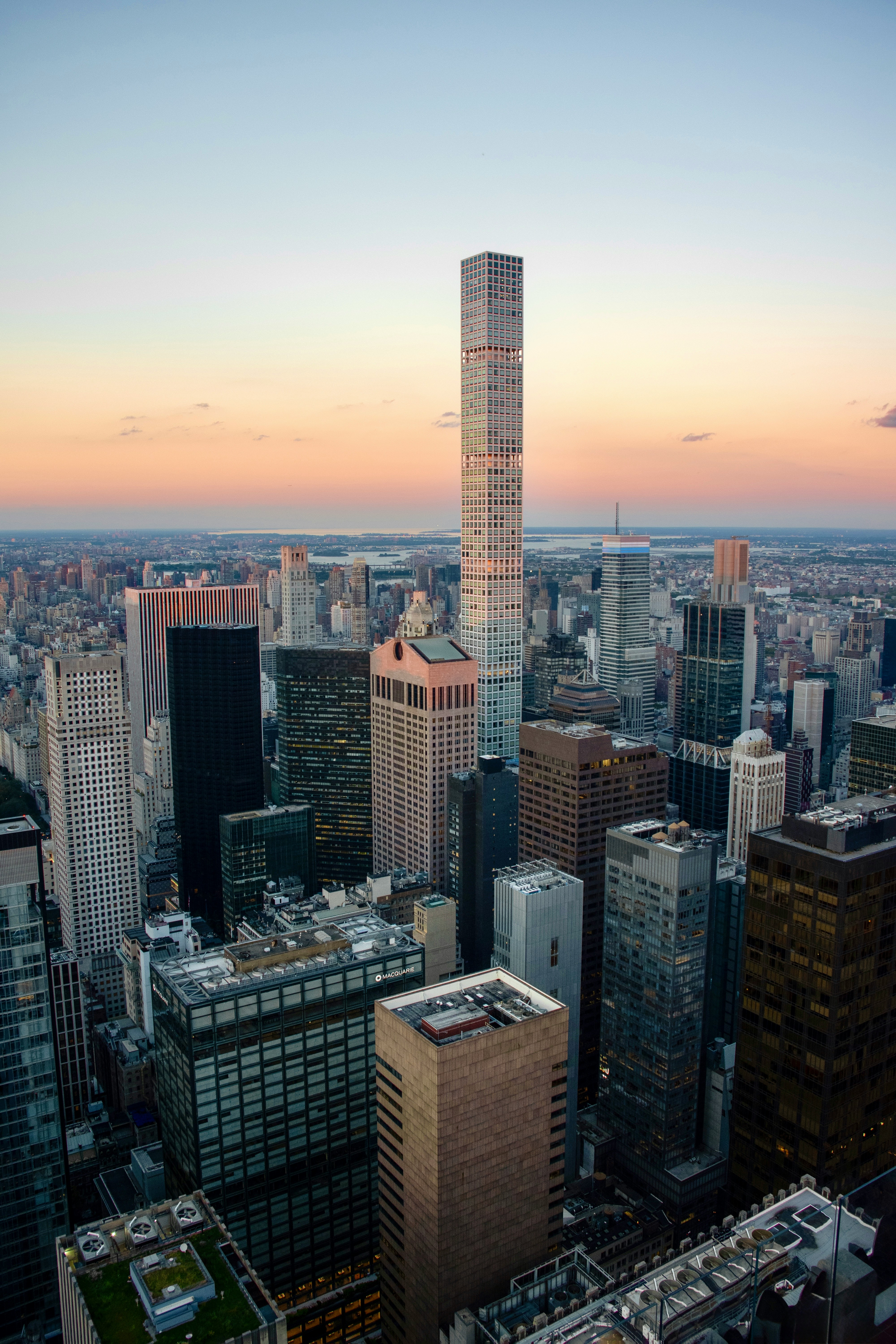 Tall skyscraper dominates a sprawling cityscape at sunset.