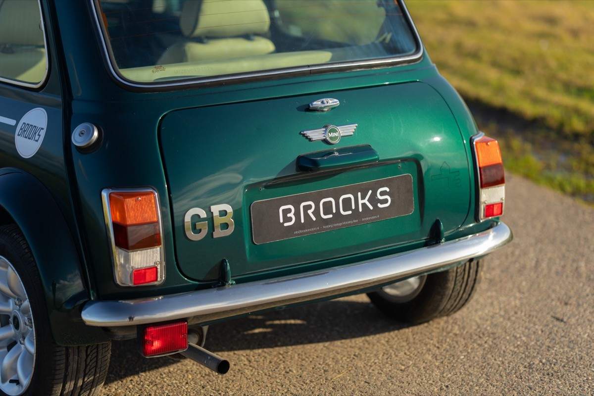 Green vintage car parked in sunlight, showing rear details, including a unique license plate.