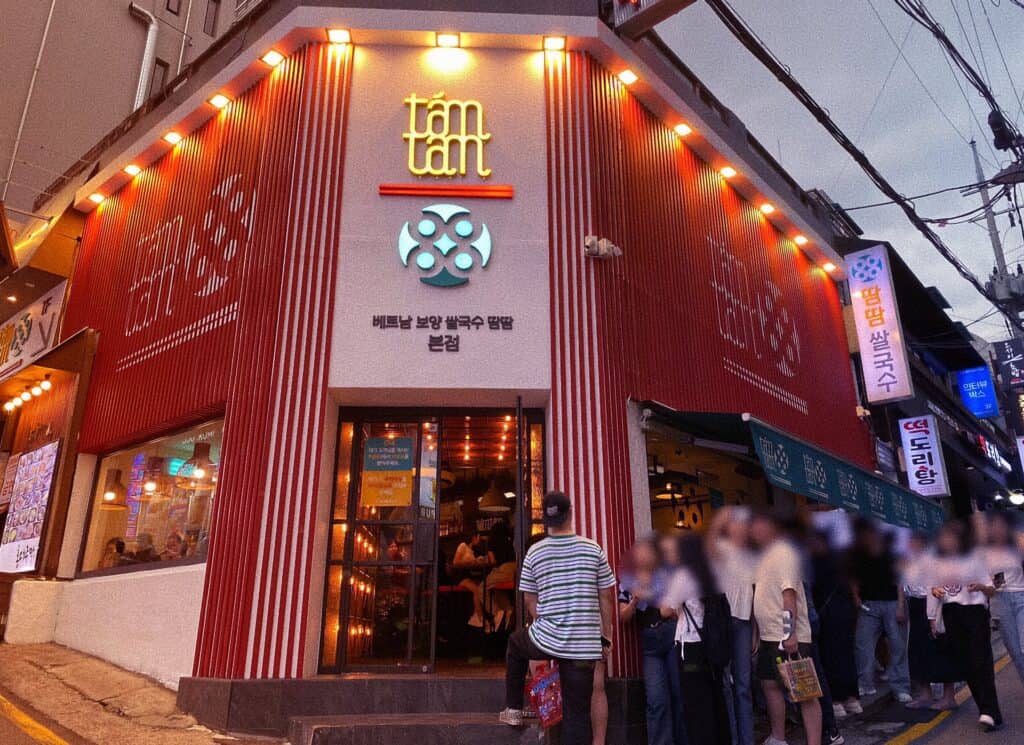 Mặt tiền quán phở Việt Nam Tám Tám (땀땀) tại Seoul với đèn vàng ấm áp và khách xếp hàng