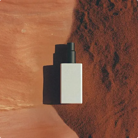 Cosmetic bottle resting on red clay
