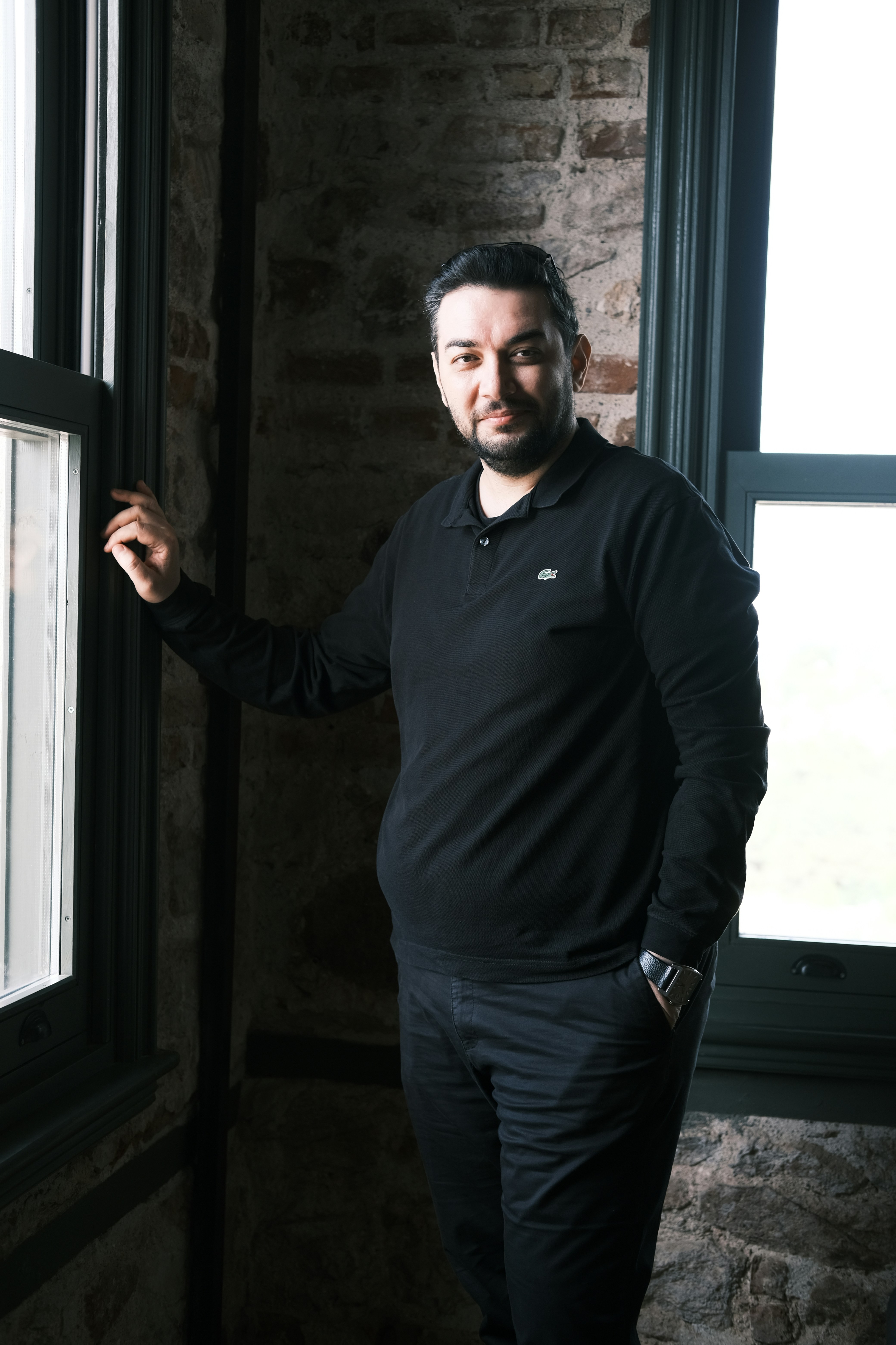 a man standing in front of a window next to a brick wall