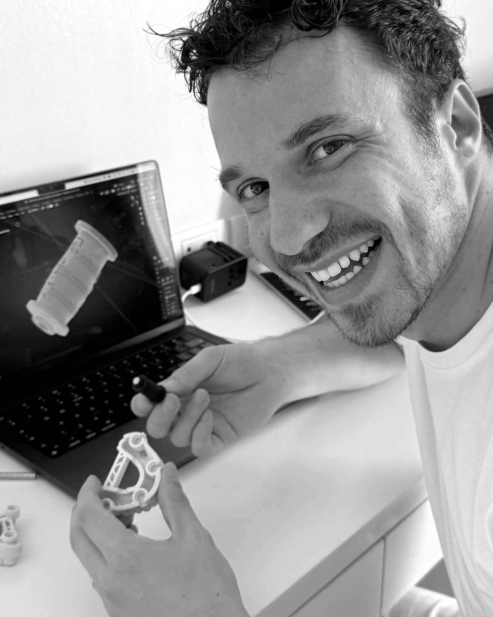 Antonello Croce holding the first GlueJet prototype and printed frame at his desk, with the CAD model on screen.