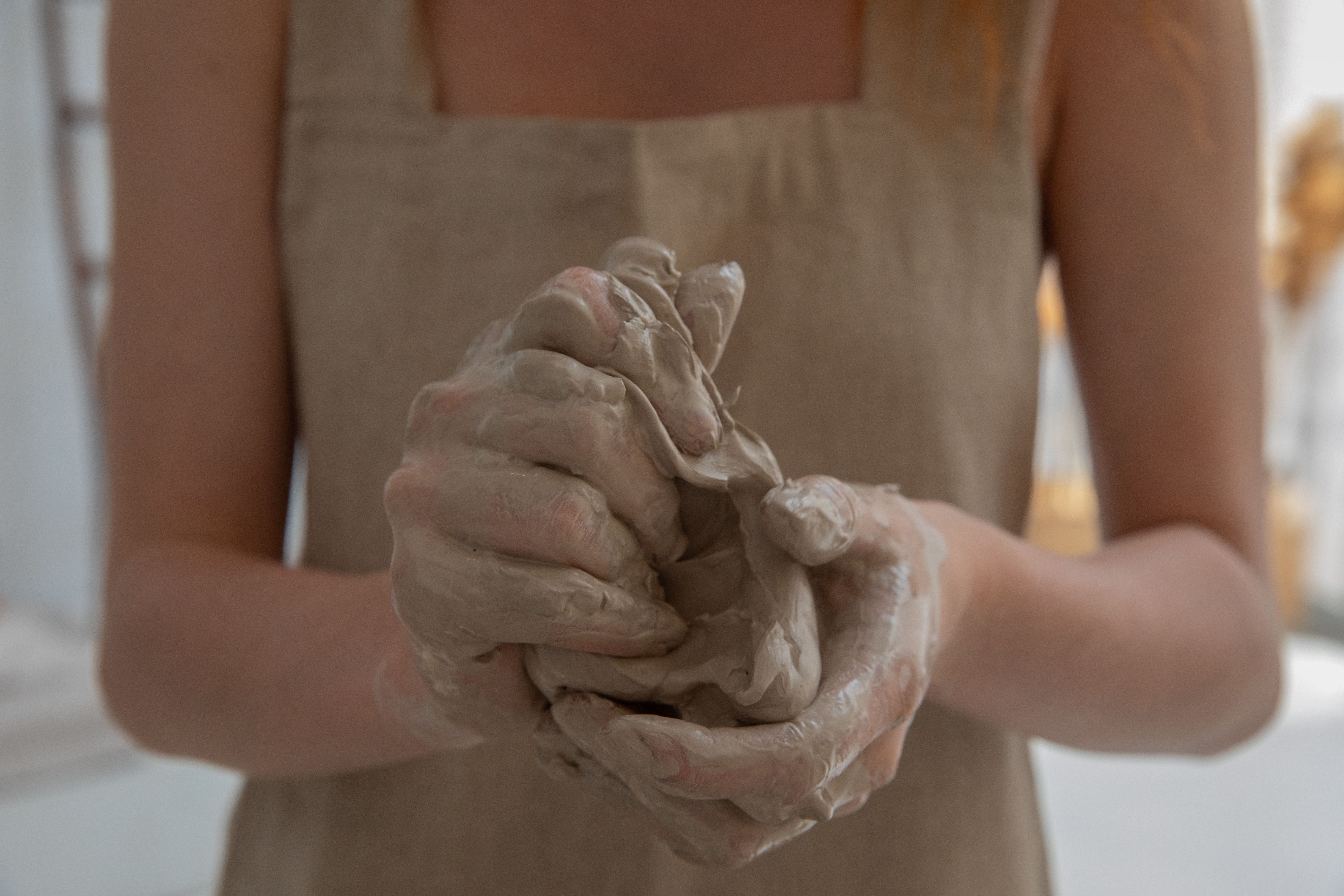 woman standing while making clay pot during daytime