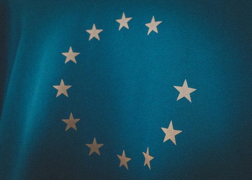 A blue background featuring a circle of 12 yellow stars, representing the European Union flag.