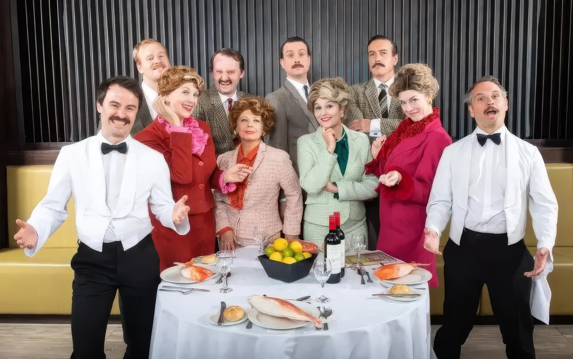 Faulty Towers dining experience cast around a table with food on