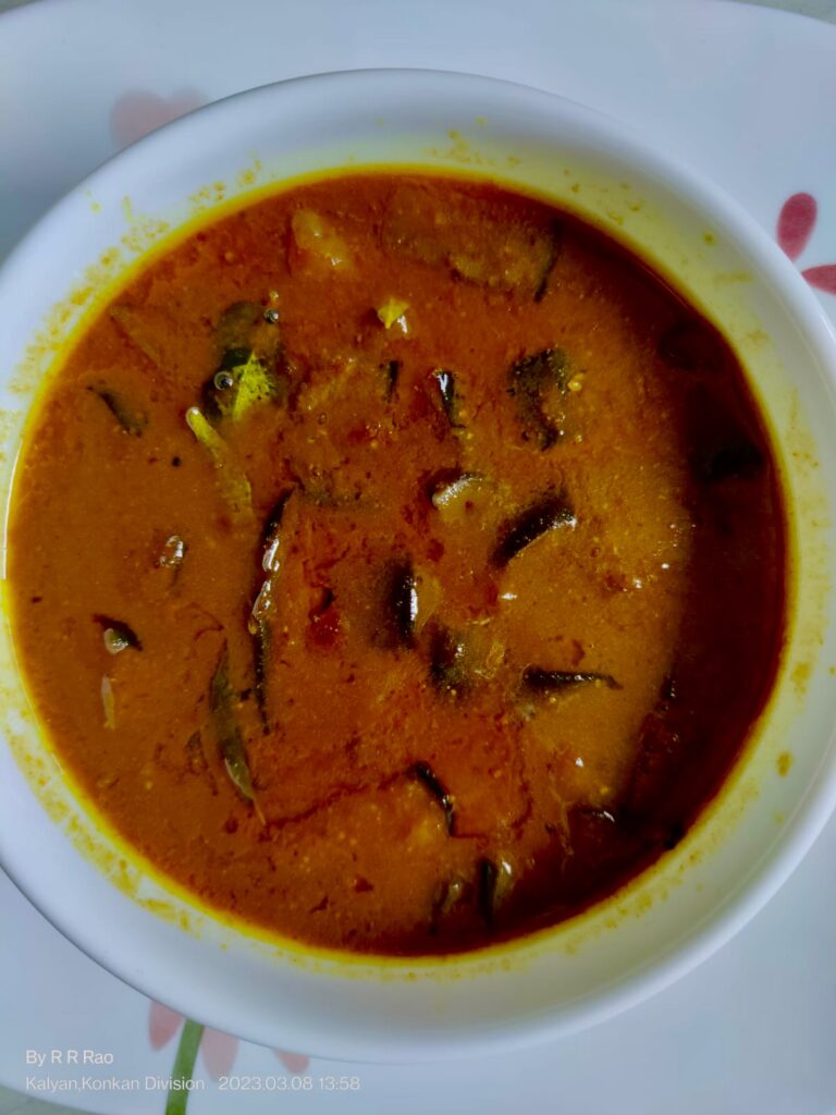 Brinjal gojju in a bowl tempered with mustard seeds and curry leaves.