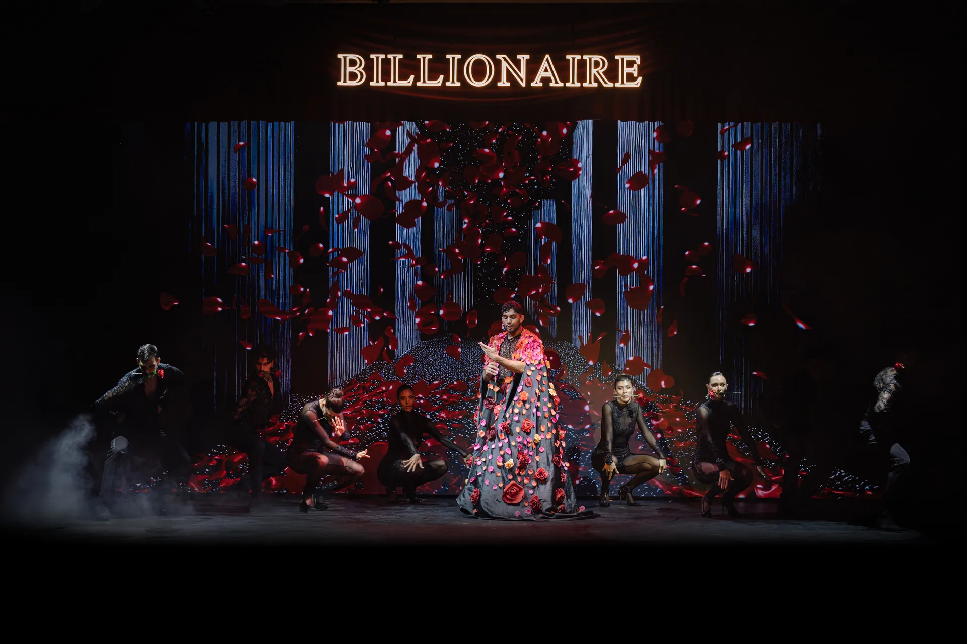 Billionaire Dubai stage with the illuminated Billionaire sign, a singer and dancers under falling rose petals