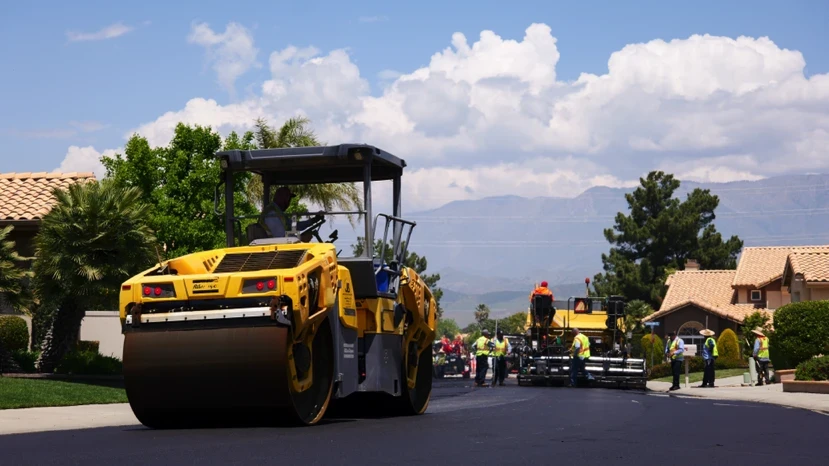 Rolling machine compacting new asphalt pavement on paving project