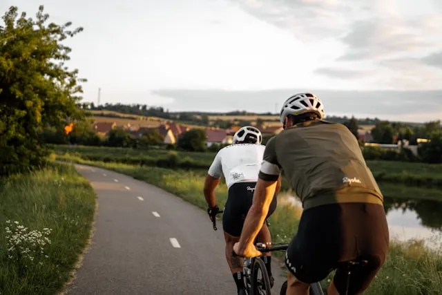 Two cyclists riding on a country road at dusk