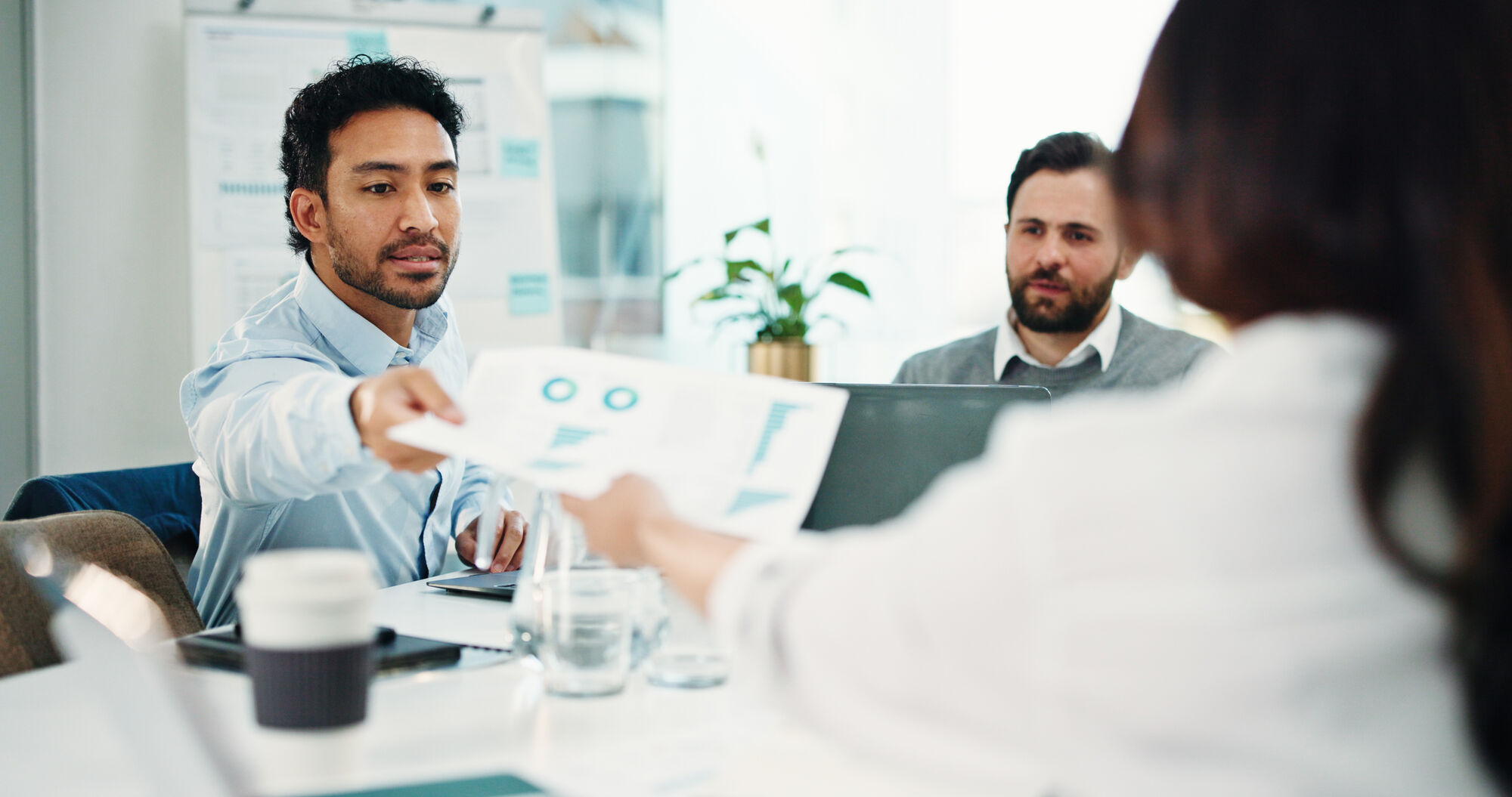 Two people working together on an electronic component, focused on a circuit board with tools visible in the foreground.