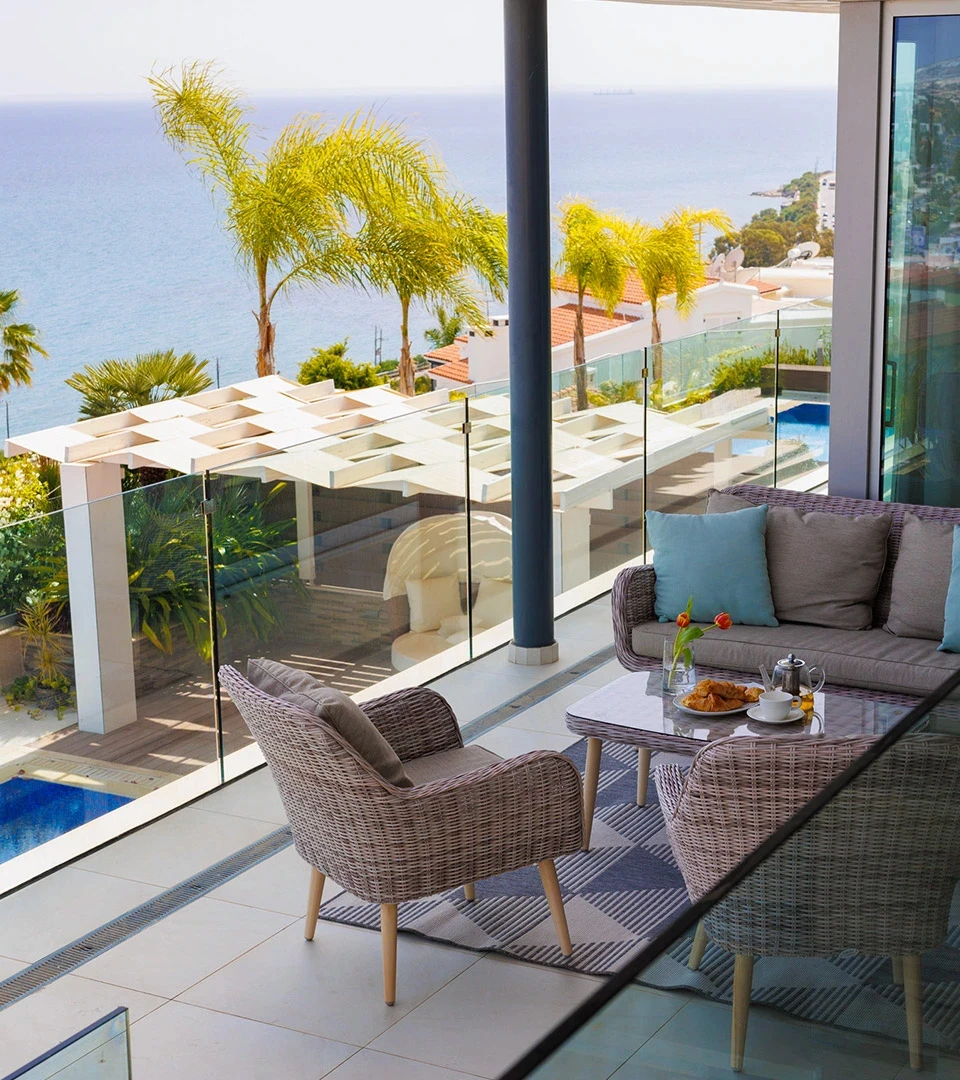 Seafront Residence Limassol sea-view terrace lounge with woven armchairs, outdoor coffee table, and panoramic Mediterranean outlook