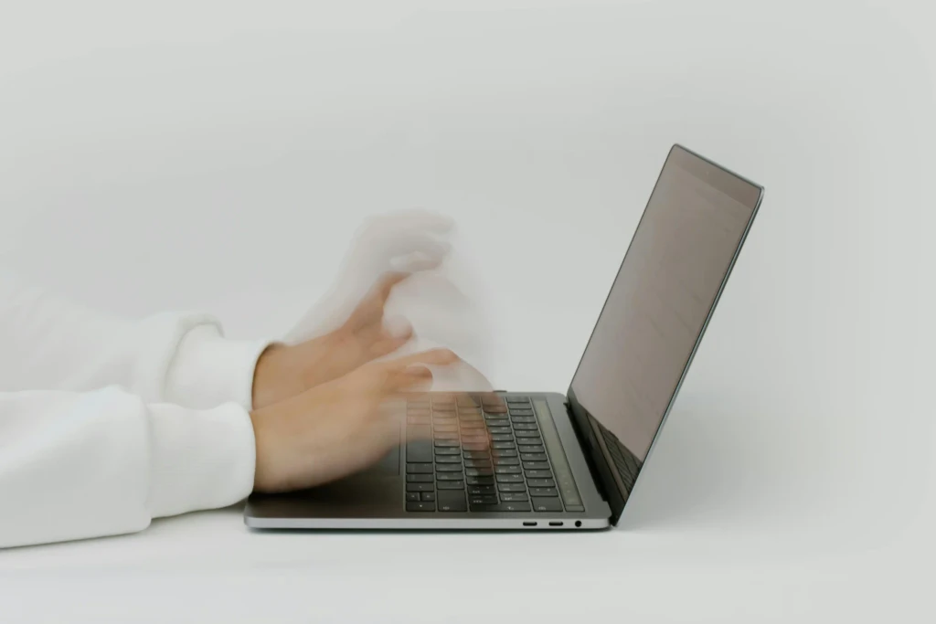 Person working quickly on a laptop with blurred hands