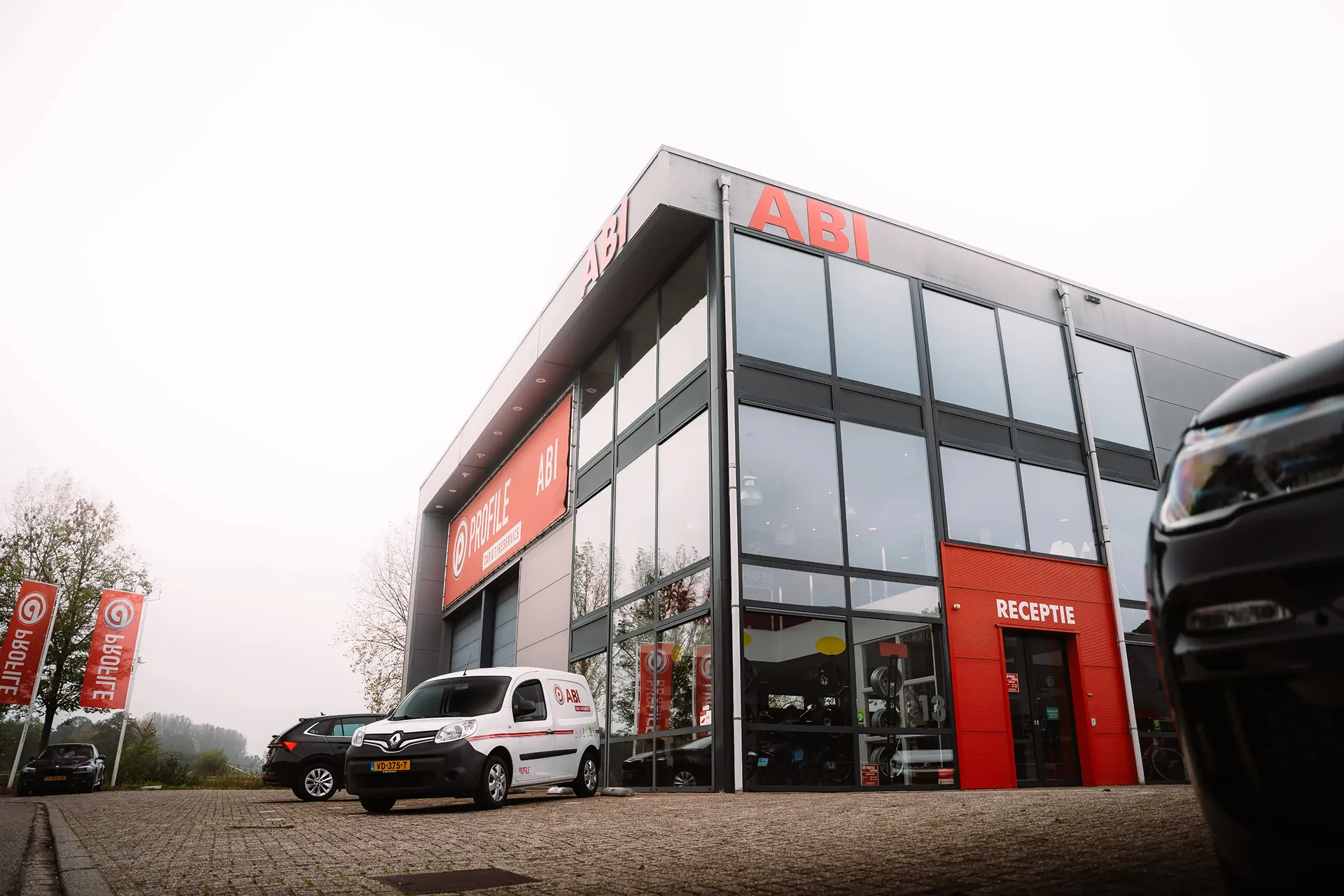 Frontside angle of car dealership abi automotive with cars in front of the building