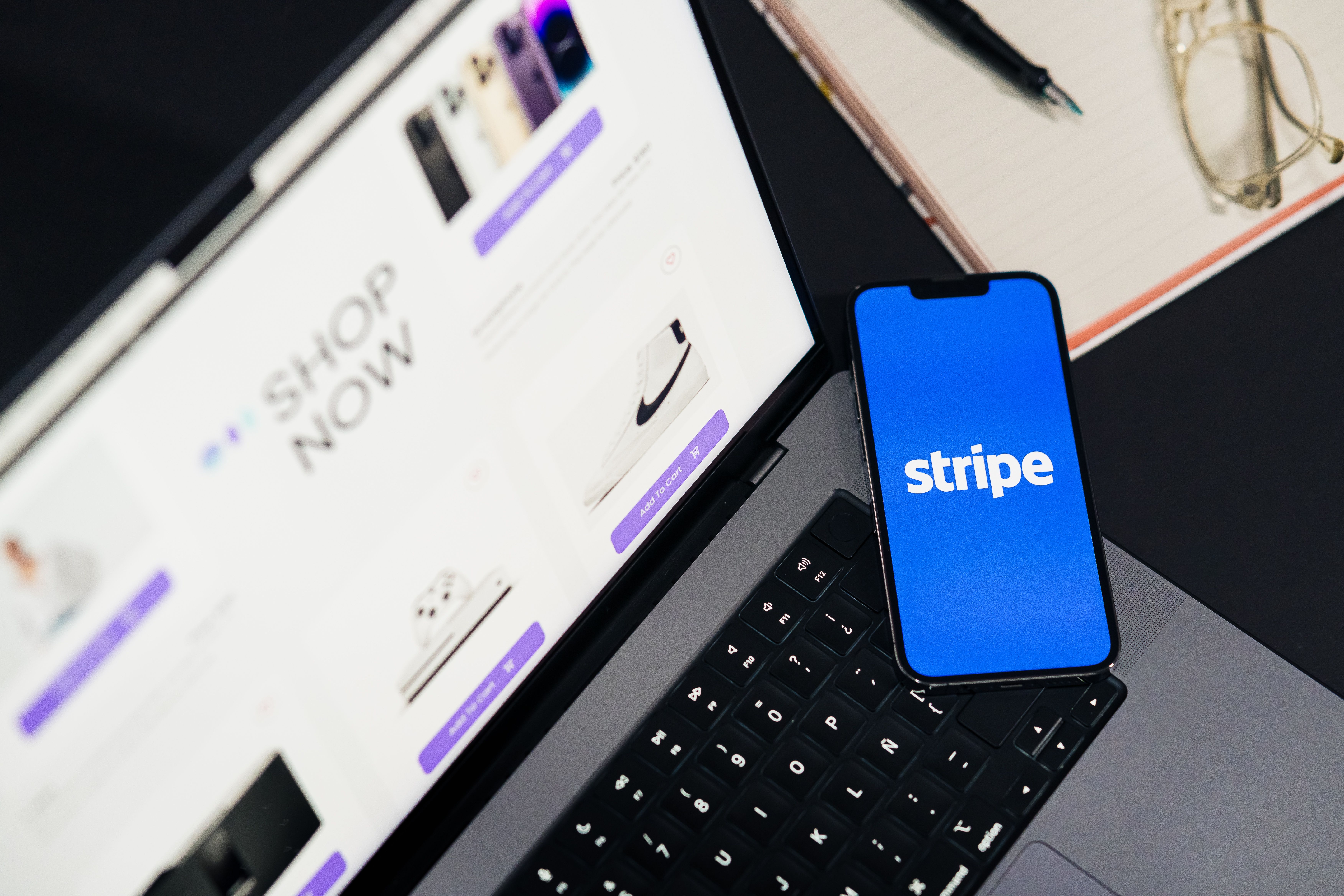 Mobile phone displaying Stripe app on a laptop with an eCommerce site open, symbolizing online shopping.