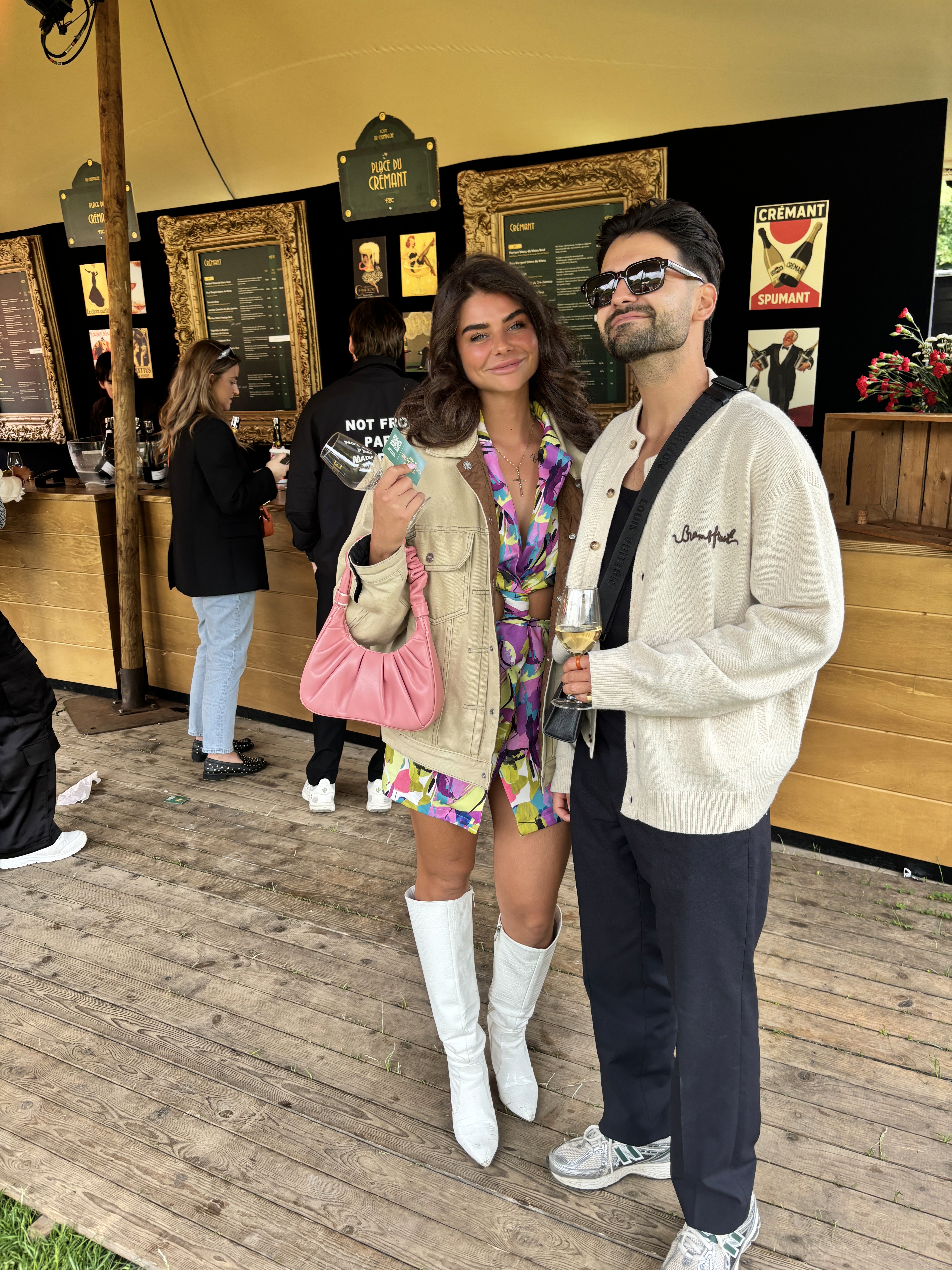 A view from an airplane window shows the aircraft's wing with a golden hue reflecting the setting sun, against a serene backdrop of fluffy clouds and a clear sky.