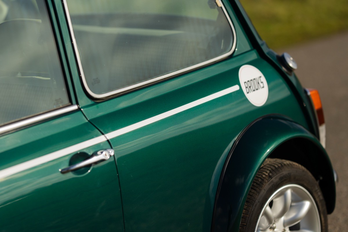 Close-up of a green vintage car, focusing on the curved tail end and fuel cap detail.