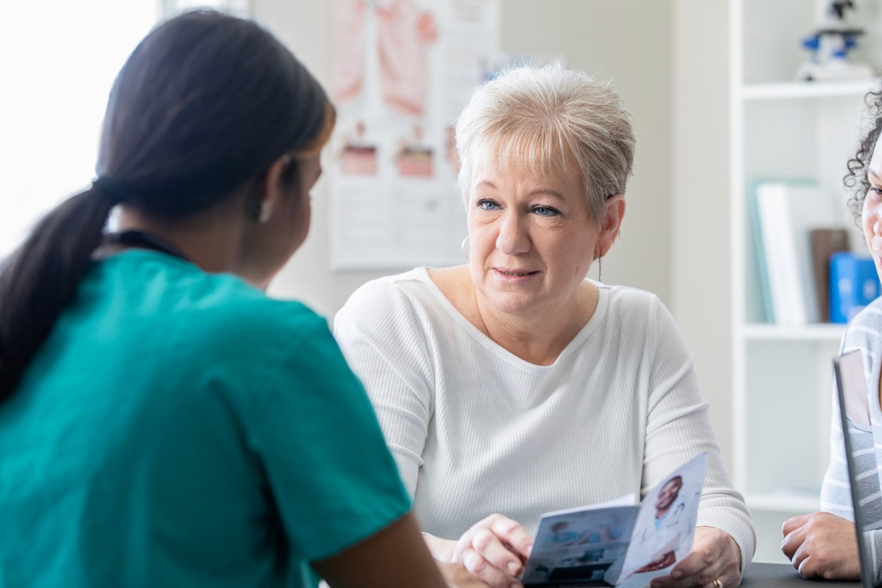 Healthcare worker and senior with brochure