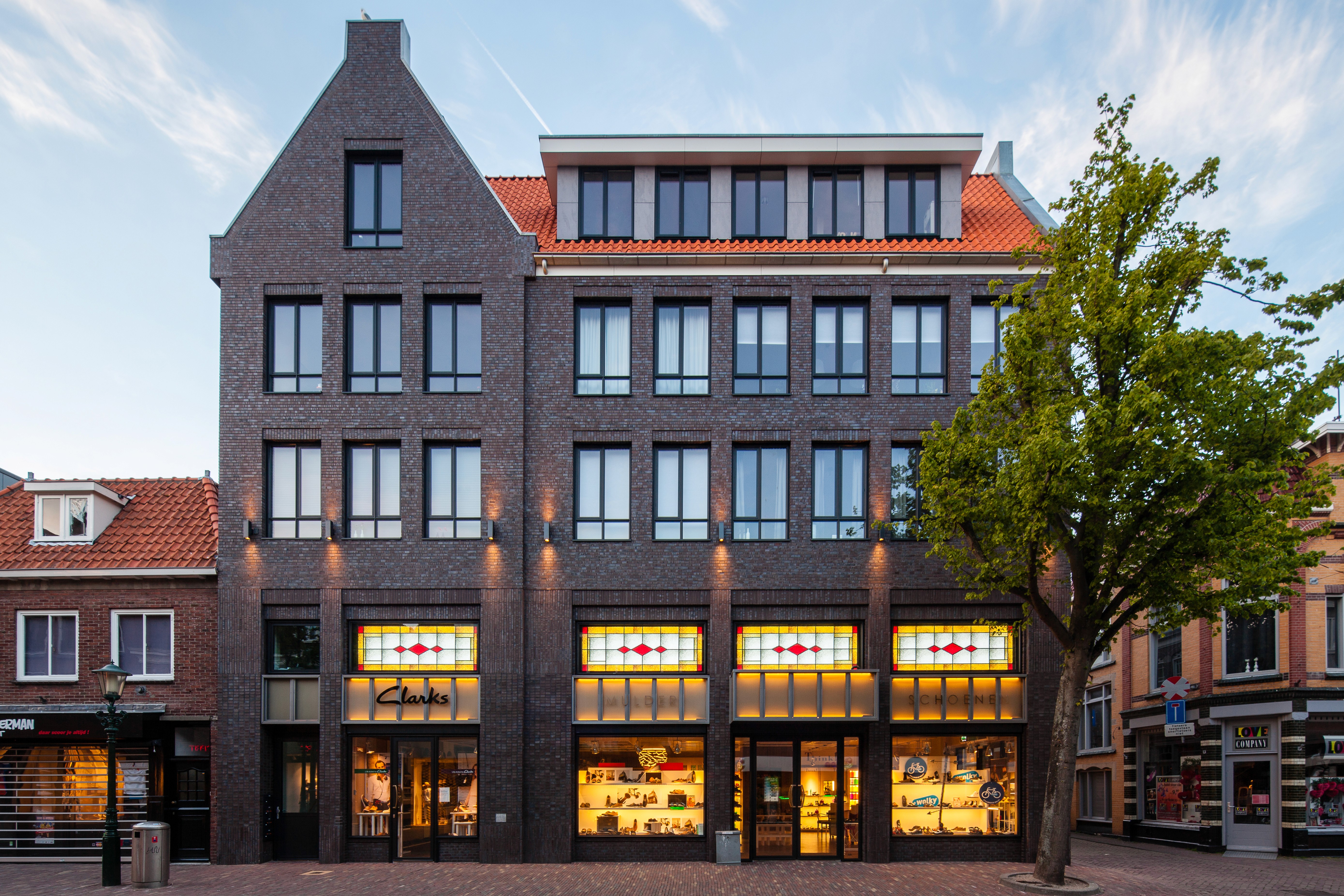 Een bakstenen gebouw met een Clarks-winkel en andere winkels op de begane grond.
